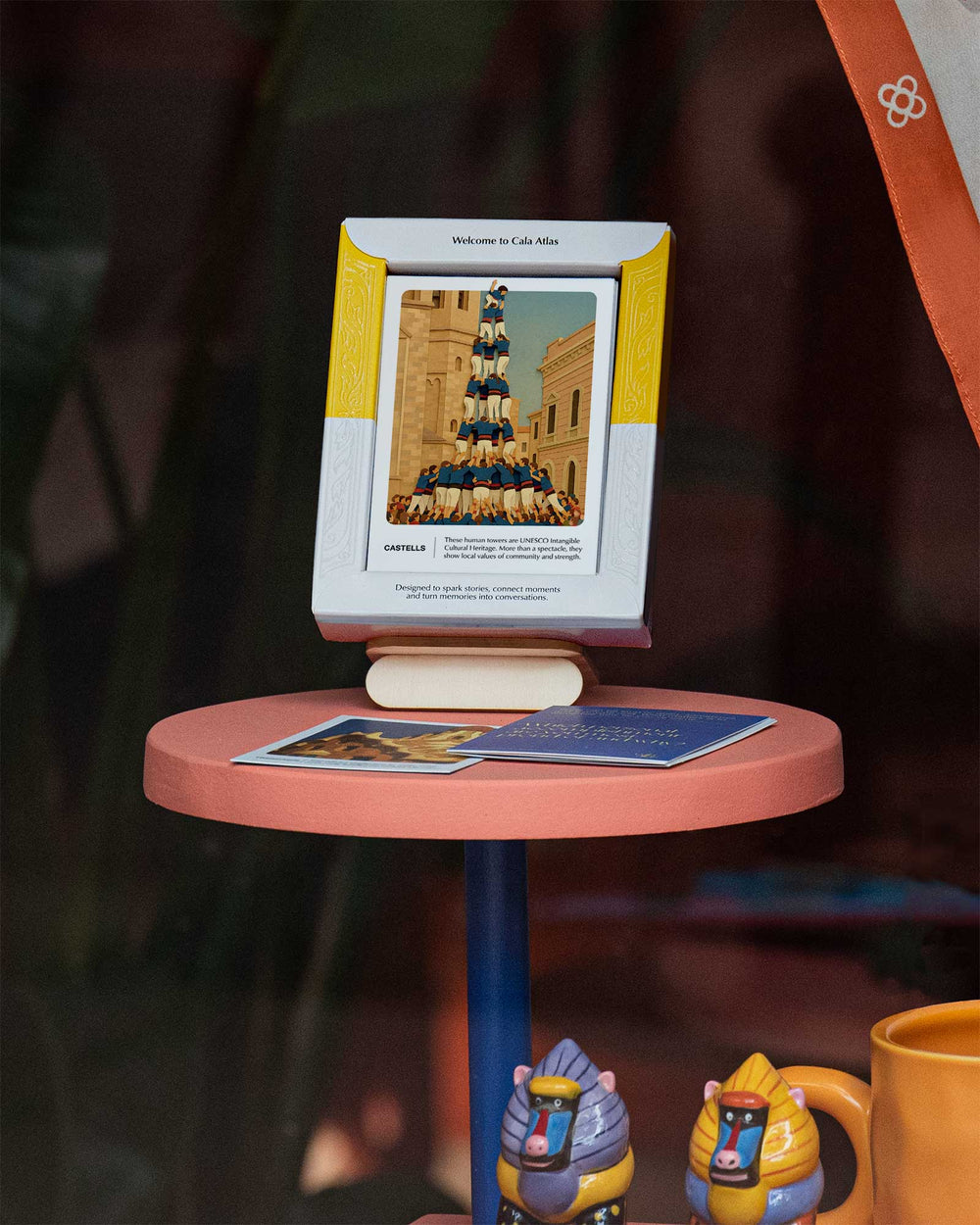 Barcelona Story Deck by Cala Atlas displayed on a pink table, featuring the Castells card with props and decorative objects around