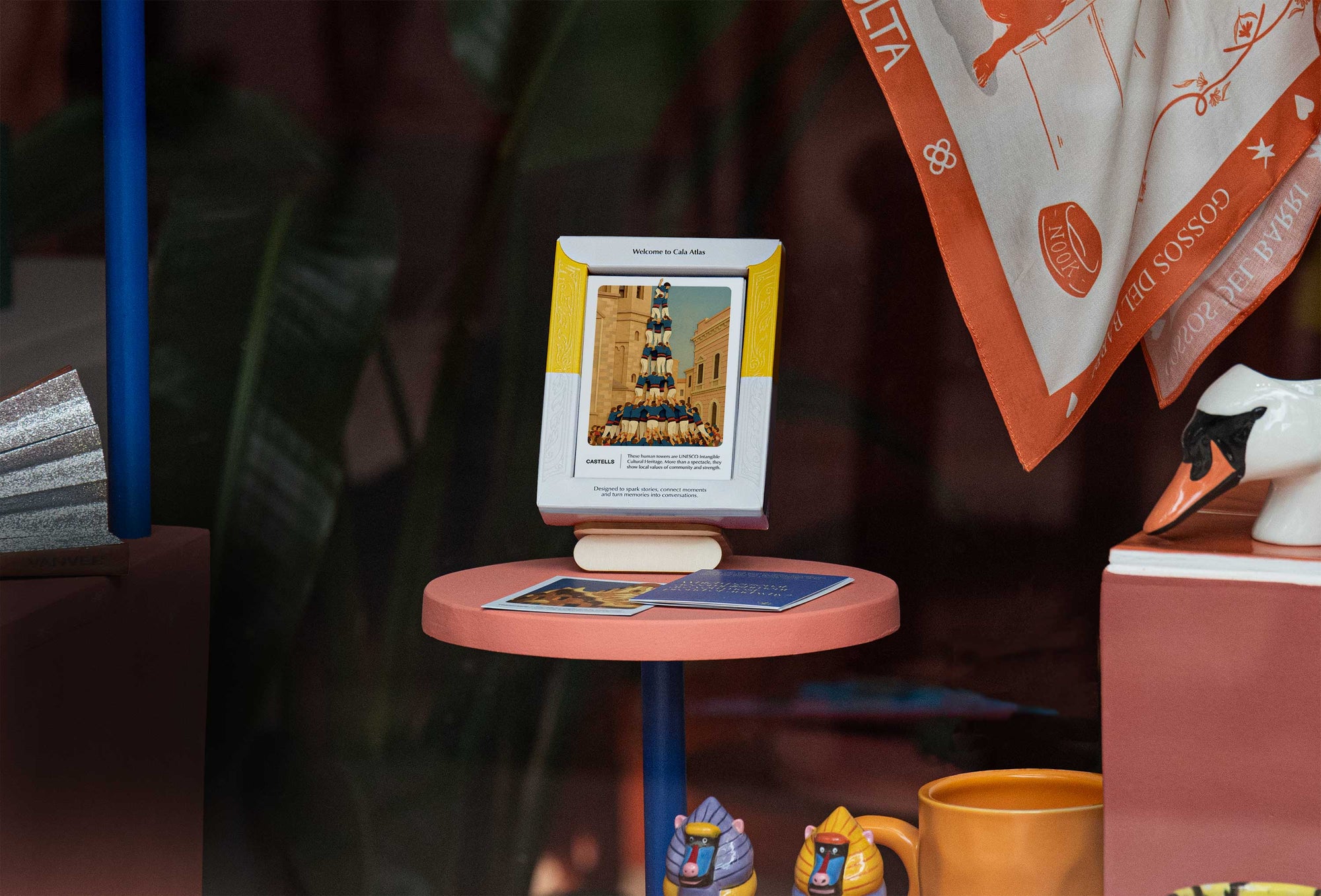 Barcelona Story Deck by Cala Atlas displayed on a pink table, featuring the Castells card with props and decorative objects around