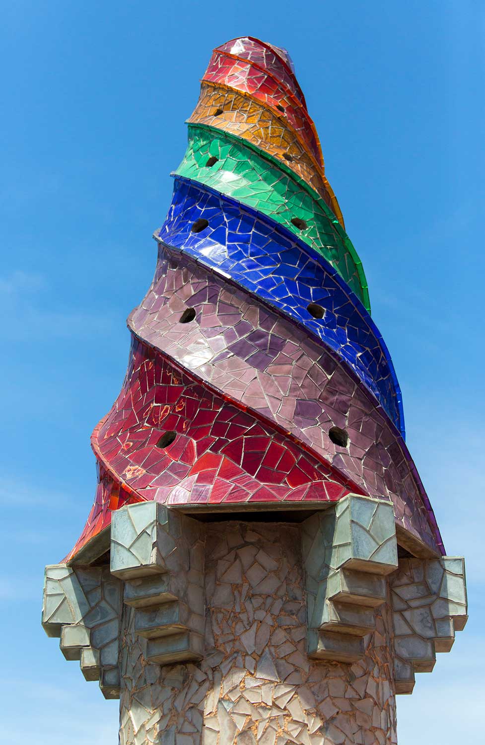 Spiral tower covered in multicoloured mosaic tiles against a clear blue sky