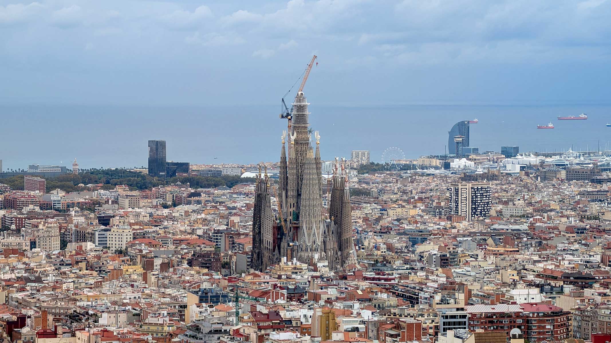 Aerial view of the Sagrada Família surrounded by Barcelona’s cityscape with the sea and cargo ships in the background